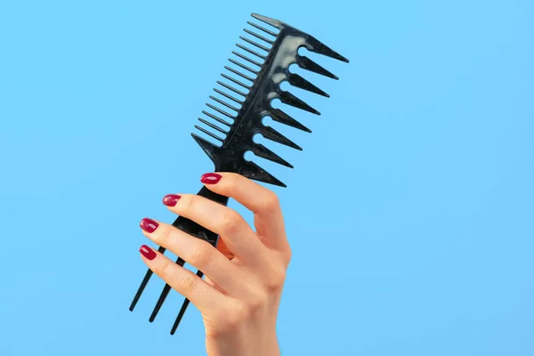 Női kéz gazdaság haj fésű ellen kék háttér — Stock Fotó