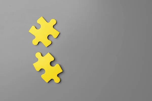 Amarelo peças de quebra-cabeça no fundo cinza perto — Fotografia de Stock