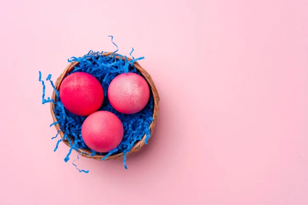 Œufs de Pâques peints dans un nid décoratif sur fond rose — Photo