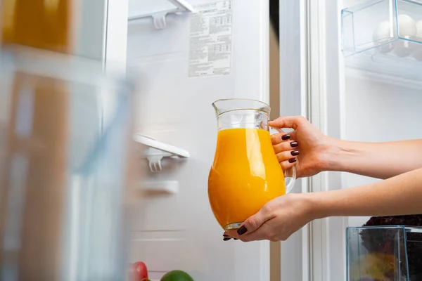 Vrouwelijke hand neemt sinaasappelsap pot uit een koelkast — Stockfoto