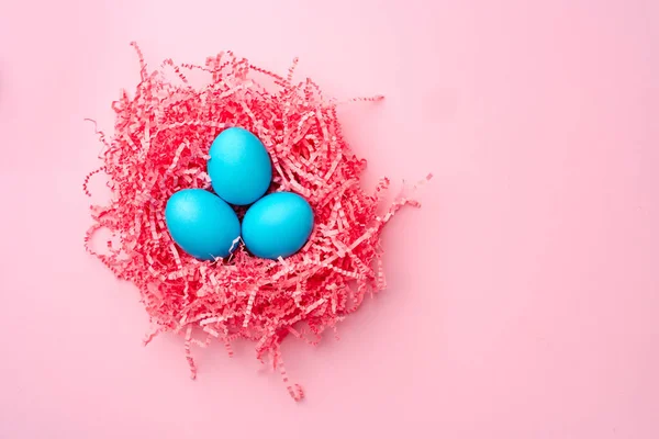 ピンクの背景に装飾的な巣の中にイースターの卵を描いた — ストック写真