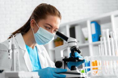 Genç bilim kadını laboratuvarda mikroskop kullanıyor.