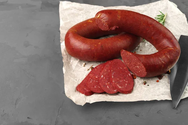 Kiełbasa mięsna na pergaminie na szarym tle — Zdjęcie stockowe