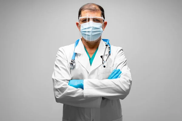 シニア男性医師上の顔マスクスタンディングとともに灰色の背景 — ストック写真
