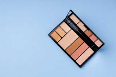 Cilt makyaj ürünleri ve mavi arkaplanda fırça