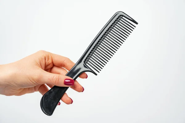 Female hand holding hair comb against white background — Stock Photo, Image