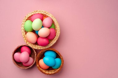 Pembe arka planda dekoratif yuvada boyanmış Paskalya yumurtaları