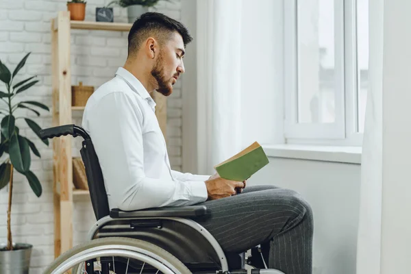 車椅子の障害者が屋内で本を読む — ストック写真