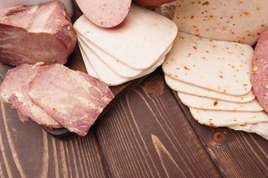 Kahverengi ahşap zemin üzerine farklı sosisler serilmiş.