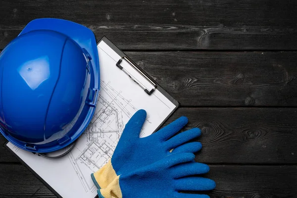 Hårdhatt, handskar och ritningar av en byggare — Stockfoto