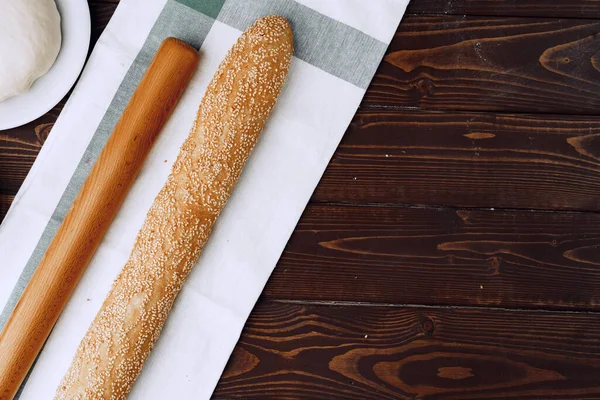 Baguette bread on brown wooden board close up