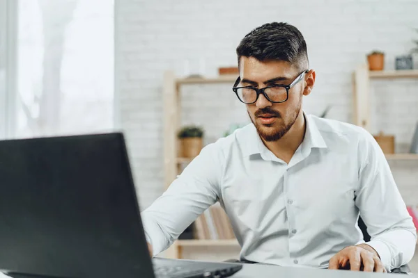 Ung framgångsrik affärsman som använder bärbar dator vid sitt skrivbord — Stockfoto