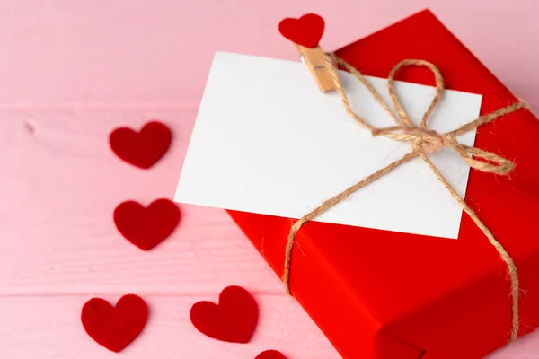 Caja de regalo roja y tarjeta de felicitación sobre fondo rosa — Foto de Stock