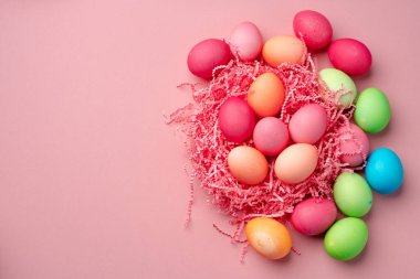 Pembe arka planda dekoratif yuvada boyanmış Paskalya yumurtaları