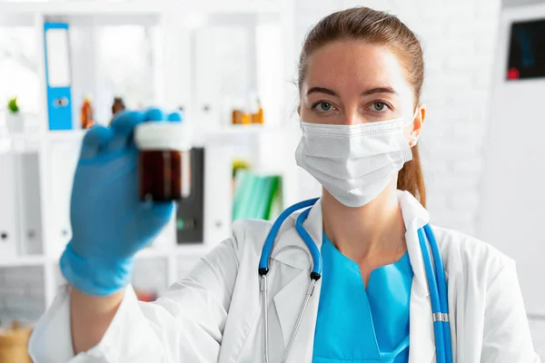 Maskeli kadın doktor elinde cam kavanozla ilaç tutuyor. — Stok fotoğraf