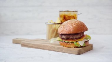 Sodayla servis edilen taze lezzetli hamburger ve beyaz masada kızarmış patates.