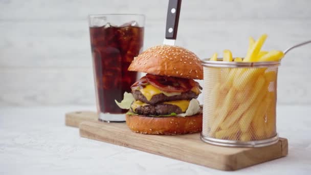 Burger segar disajikan dengan soda dan kentang goreng di atas meja putih — Stok Video