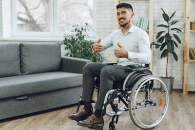 Mutlu gülümseyen genç adam evde tekerlekli sandalyede