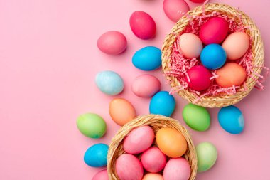 Pembe arka planda dekoratif yuvada boyanmış Paskalya yumurtaları
