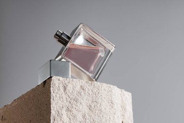 Gri tuğla üzerinde şeffaf bir koku şişesi.