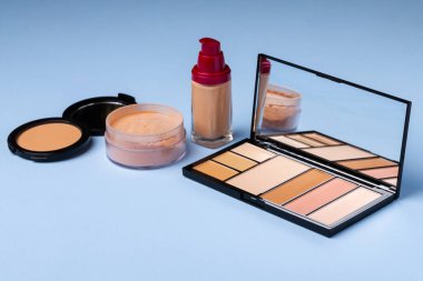 Cilt makyaj ürünleri ve mavi arkaplanda fırça