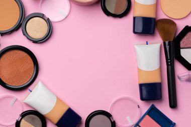 Cilt makyaj ürünleri ve pembe arka planda fırça