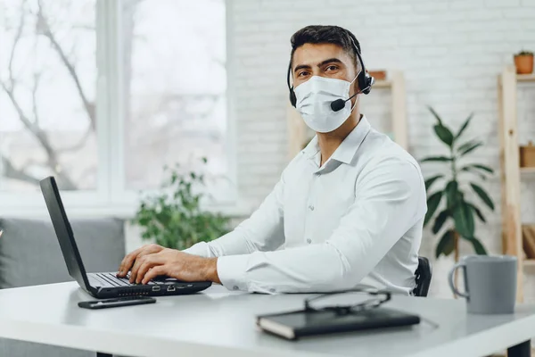 Young businessman sitting at his working desk with medical mask on — Stock Photo, Image