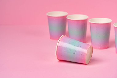 Pembe arka planda tek kullanımlık pembe bardaklar.