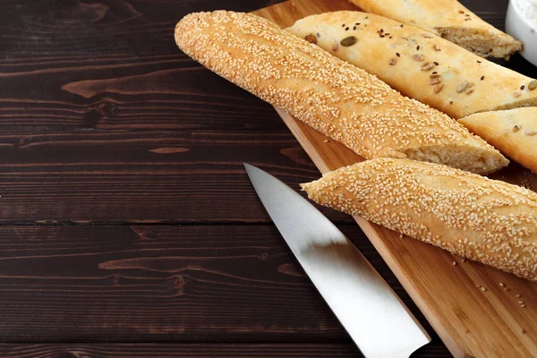 Baguette chleb na brązowej drewnianej desce zbliżenie — Zdjęcie stockowe
