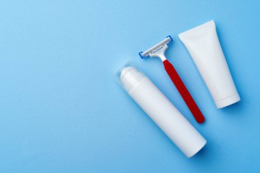 Mavi arka planda tıraş köpüğü ve tek kullanımlık tıraş makinesi.