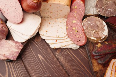 Kahverengi ahşap zemin üzerine farklı sosisler serilmiş.