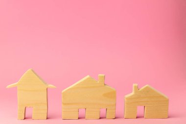 Pembe arka planda ahşap ev minyatürü yakın plan.