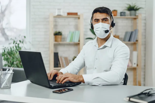 Young businessman sitting at his working desk with medical mask on — Stock Photo, Image
