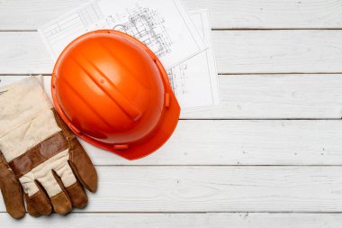 Sert şapka, eldivenler ve bir inşaatçının planları.
