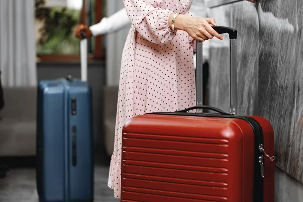 Hombre y mujer irreconocibles con maletas de pie cerca de la recepción en el hotel —  Fotos de Stock