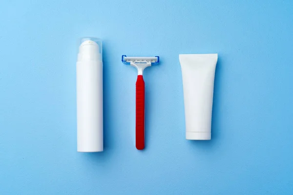 Крем для бритья и одноразовая бритва на синем фоне — стоковое фото