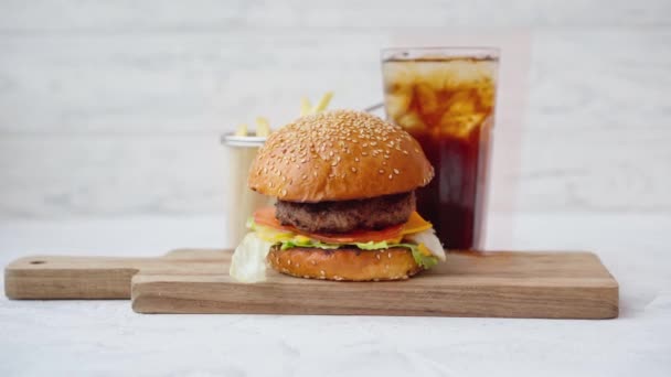 Čerstvý chutný burger podávaný se sodou a hranolky na bílém stole — Stock video