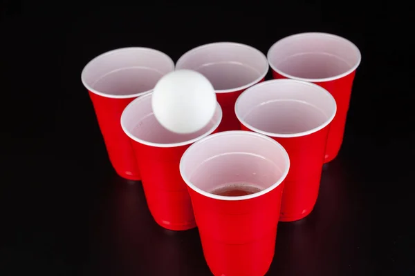 Copos de plástico vermelho e bola para o jogo de pong de cerveja — Fotografia de Stock