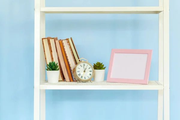 Белая металлическая стойка с книгами на синем фоне — стоковое фото
