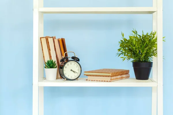 Cremalheira de metal branco com livros contra fundo azul — Fotografia de Stock