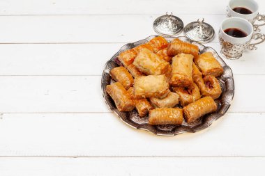 Bir fincan sıcak çay ve bir tabak Türk tatlısı.