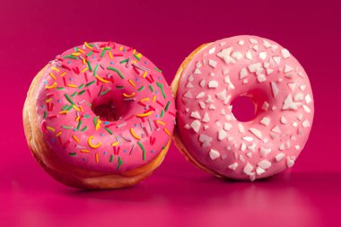 Parlak pembe bir arka planda lezzetli, yuvarlak donut.
