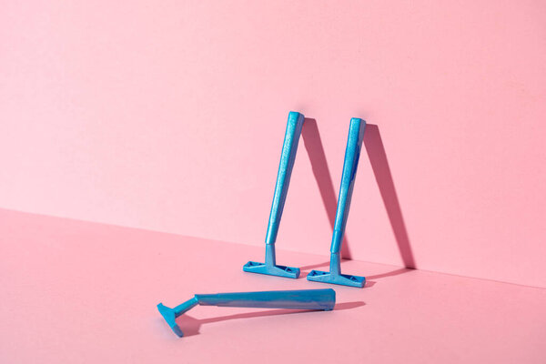 Голубые одноразовые бритвы на фоне розовой бумаги