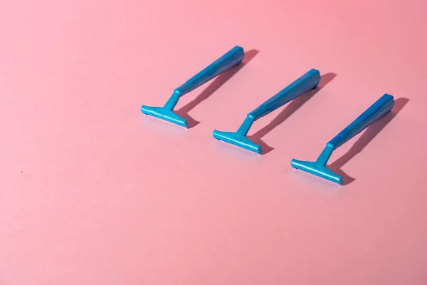 Modré jednorázové holicí strojky na růžovém papíře pozadí — Stock fotografie