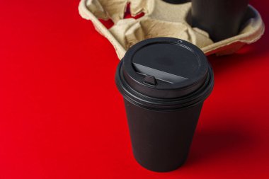 Koyu kahve fincanlarını kabın içinde götürür.