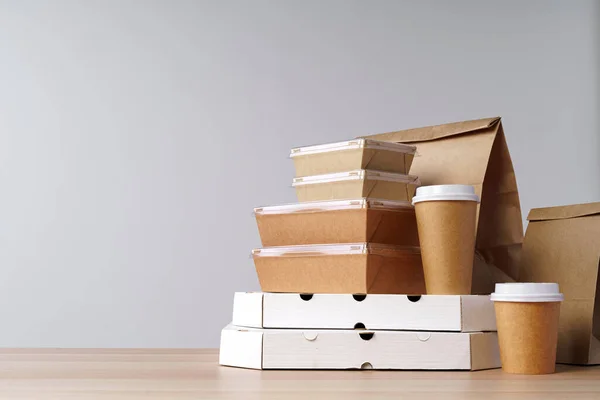 Много различных вынос продовольственных контейнеров, коробка для пиццы, кофейные чашки и бумажные пакеты на светло-сером фоне — стоковое фото