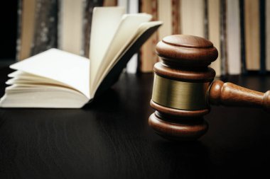 Açık kitabın arka planında kahverengi tahta yargıç tokmağı