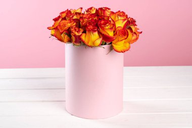 Pembe arka planda güller olan karton kutu.