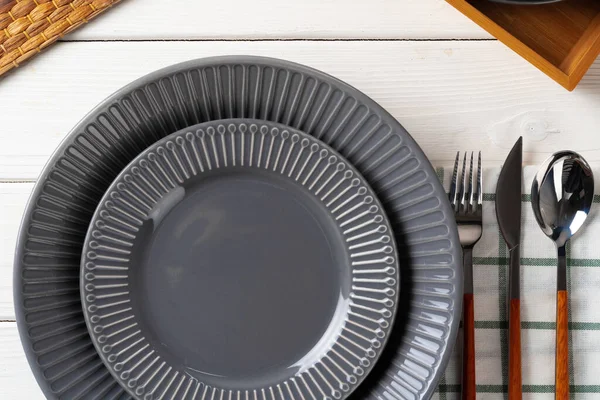 木製のテーブルの上にカトラリーと光沢のある灰色のセラミックプレート — ストック写真