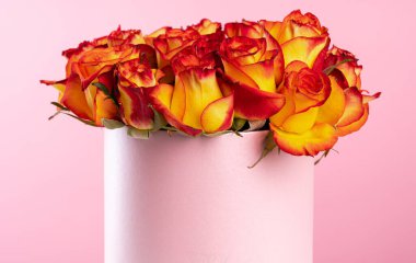 Pembe arka planda güller olan karton kutu.